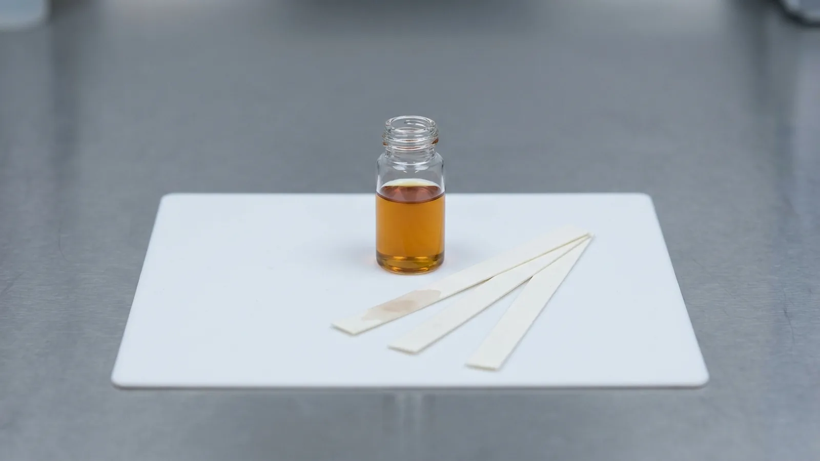 A printed GC-MS chromatogram beside a sealed bottle — how you tell real oud oil from a reconstructed imitation