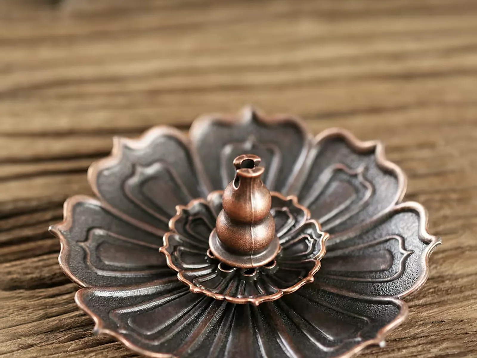 Solid brass lotus incense stand on a dark wooden table, stick seated in the centre pin