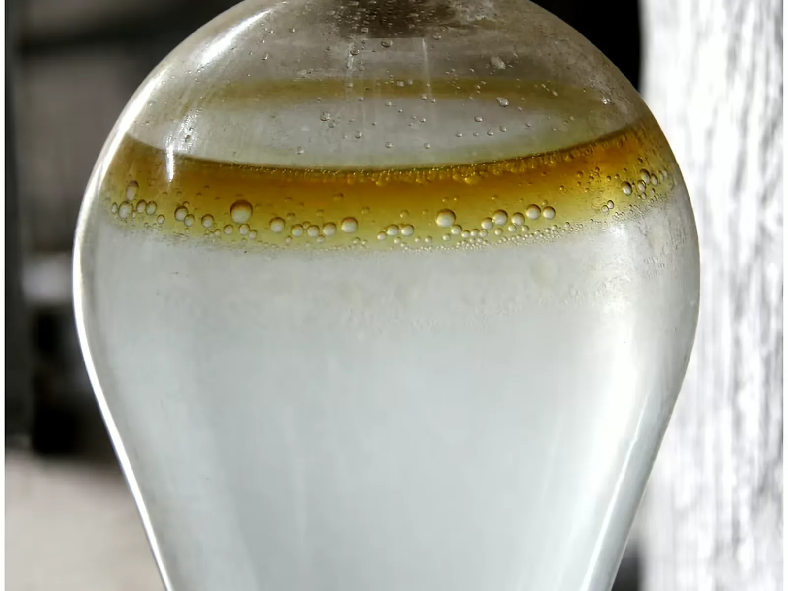 Hydro-distilled oud oil separating above the distillation water in a glass receiver
