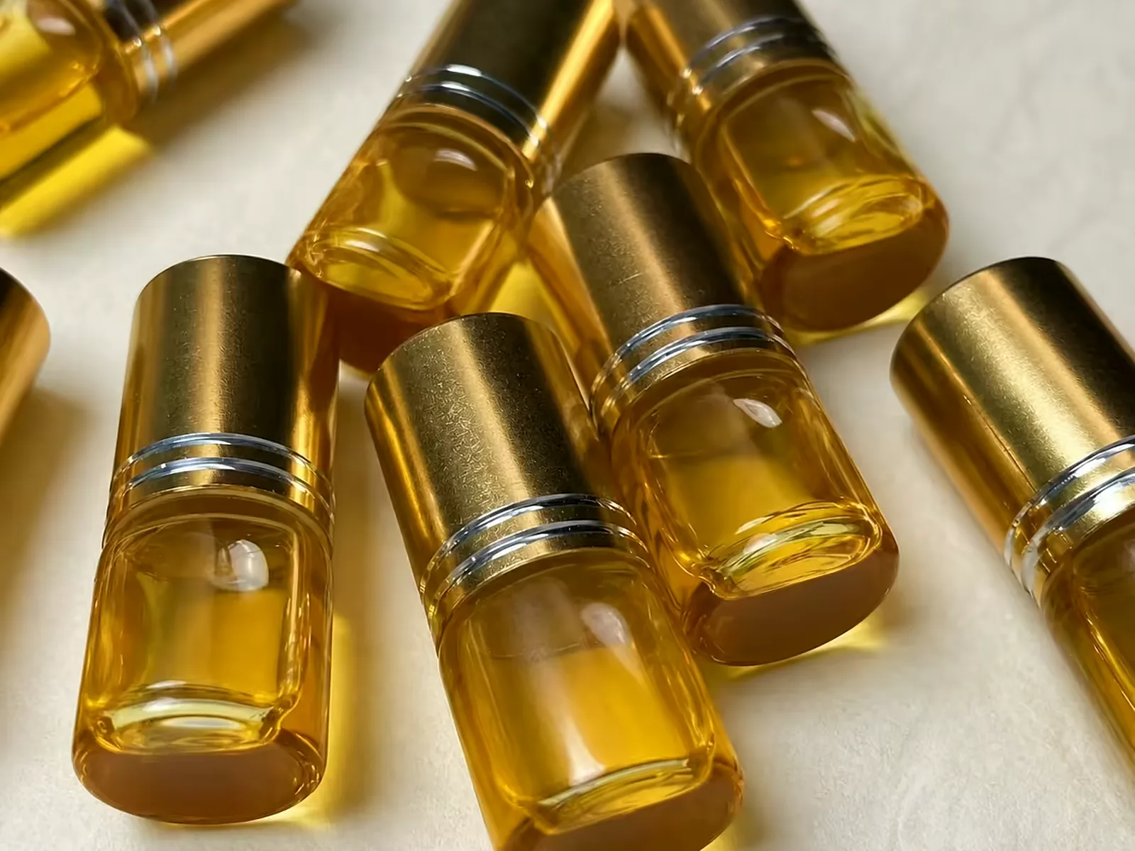 Gold-capped steel-ball roll-on bottles filled with amber oud oil, laid out on cloth